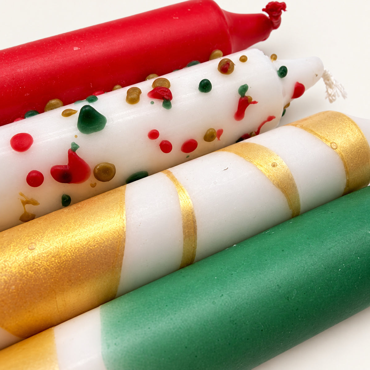 Jingle Pop – Nahaufnahme von Weihnachtsrot, bunten Wachstropfen, Goldspirale und Tannengrün