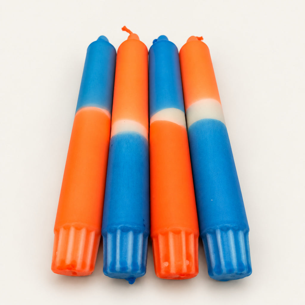 Neon Blue Flame – vier handgefärbte Stabkerzen in Neonorange und Blau auf neutralem warmweißem Hintergrund, Blick vom Kerzenfuß