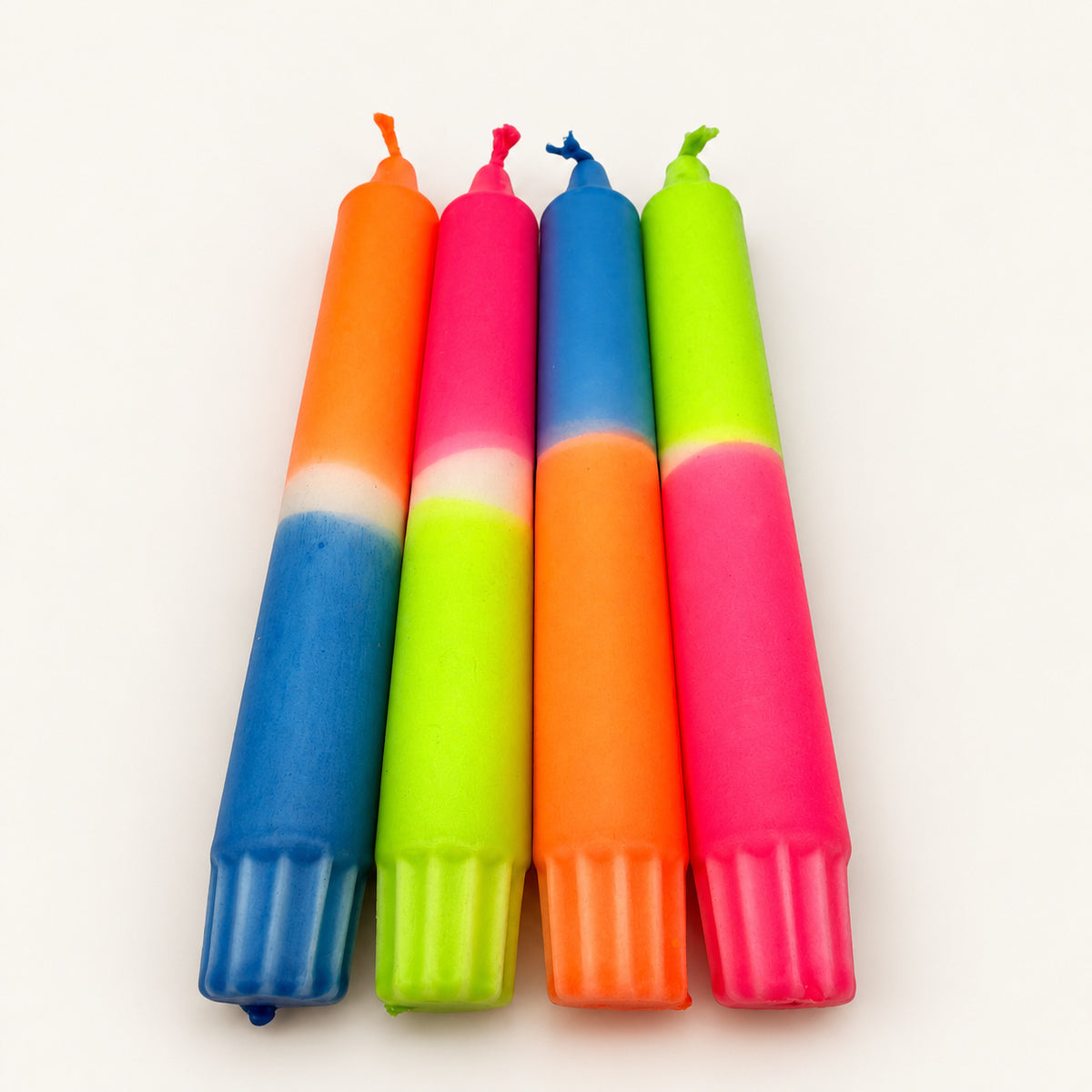 Tutti Frutti – vier handgefärbte Neon-Stabkerzen in Orange, Pink, Blau und Grün auf neutralem warmweißem Hintergrund, Blick vom Kerzenfuß